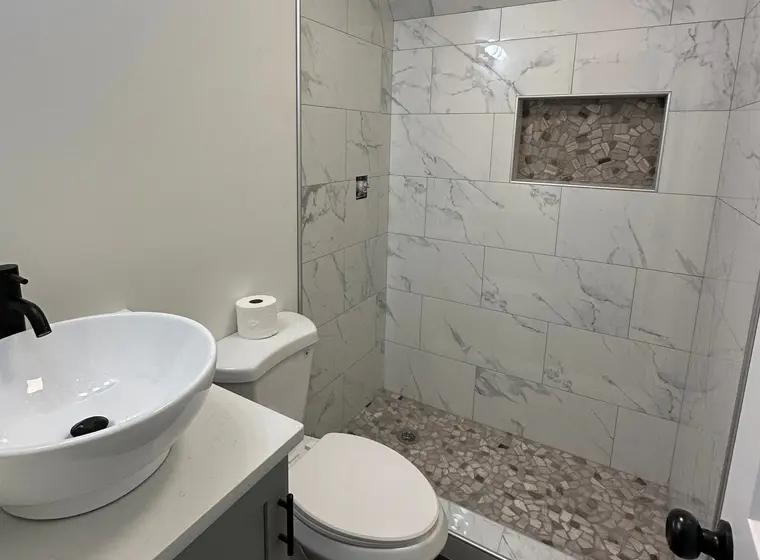 Baño de visitas con ducha de mármol, nicho de piedra de río y lavabo vessel