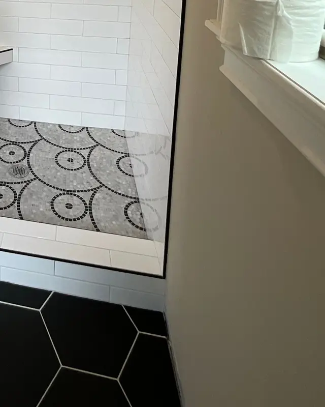 Piso de ducha en mosaico de círculos enmarcado por hexágono negro