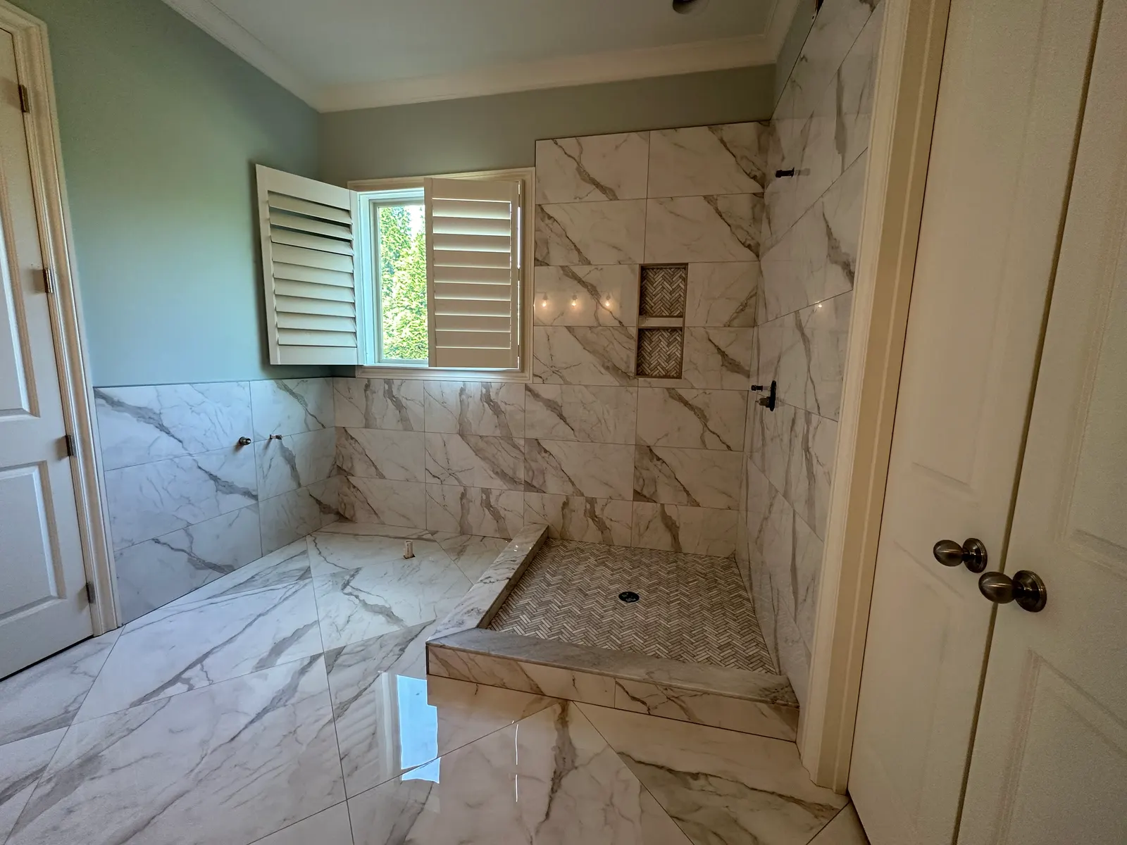 Calacatta-look walk-in shower with a shuttered window, set by B & B Pro Tile